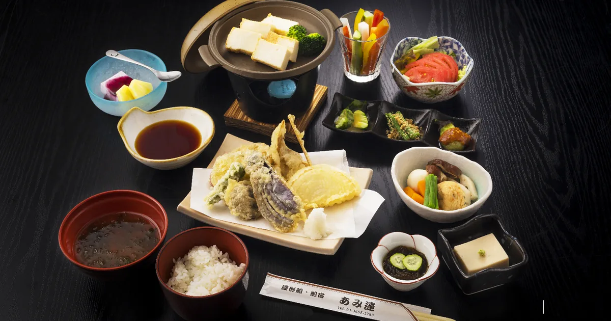 A Japanese course dinner laid out on a black tray: sashimi, tempura, small side dishes, rice and soup